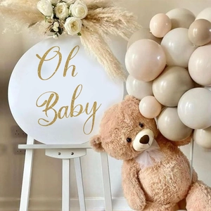 Round Oh Baby party backdrop sign with gold lettering and white tripod stand for nursery