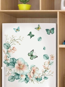 Detail of watercolor green floral and butterfly wall stickers on a white cabinet surface