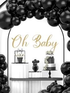 Close-up of matte black balloon arch set with golden Oh Baby wall sign for party decor