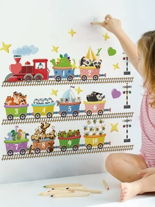 Detail showing a girl placing colorful cartoon animal number train stickers on a white wall