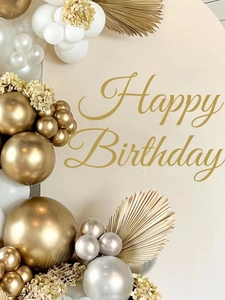 Detail of golden Happy Birthday balloon set with dried palm leaves and floral decorations
