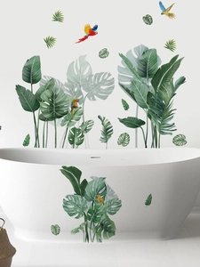 Détail de stickers muraux avec feuilles de monstera et perroquets sur une baignoire blanche