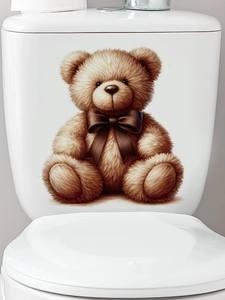 Close-up of a brown teddy bear wall sticker with a coffee bow on a white toilet tank