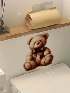 Detailed view of a 3D teddy bear wall sticker with a bow on a white bathroom wall