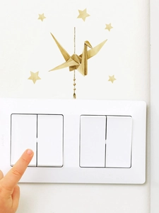 Detailed view of watercolor origami crane and gold stars wall decals around a light switch