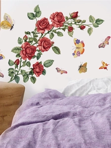 Détail de stickers muraux avec roses rouges et papillons sur un mur blanc de chambre