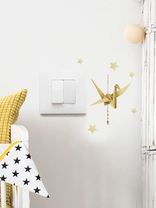 Detail of golden origami crane and star wall decals near a white light switch panel