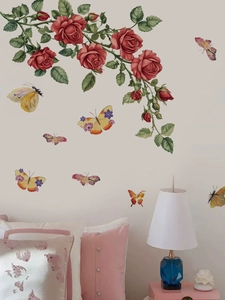 Détail du mur de chambre avec stickers roses rouges et papillons colorés au-dessus du lit