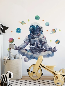 Nursery room wall detail with meditating astronaut sticker and colorful planets decal