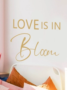 Dettaglio dell'adesivo murale dorato Love is in Bloom su una parete minimalista