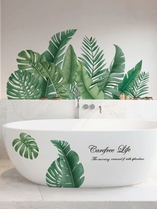 Detail showing tropical monstera leaves and Carefree Life text stickers on a bathroom wall