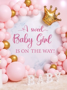 Detail view of pink and gold baby shower balloon arch with glowing BABY letters and backdrop