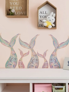 Close-up of five dreamlike mermaid tail wall stickers with gold glitter details on wall