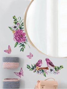 Detail of pink floral wall decals with birds and butterflies on a white wall near a round mirror