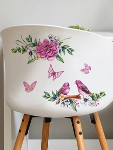 Detail view of pink floral and bird wall decals applied on a minimalist white wooden chair