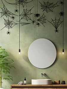 Close-up of black spider web wall decals on a green bathroom wall with a circular mirror