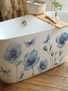 Dettaglio di adesivi con fiori blu e farfalle applicati su una vasca da bagno bianca