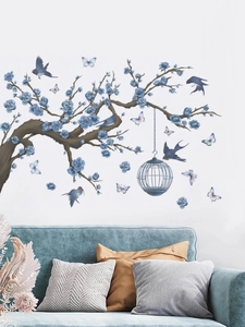 Detail of floral wall stickers with birdcage and flying birds over a blue sofa