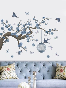 Detail of floral wall sticker with birds and cage above a sofa in a living room