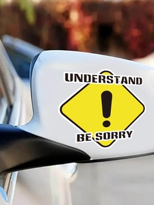Detail showing a yellow diamond warning sticker on a car side mirror with caution text