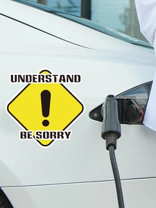 Detail of yellow diamond warning sticker with exclamation mark on a white electric car
