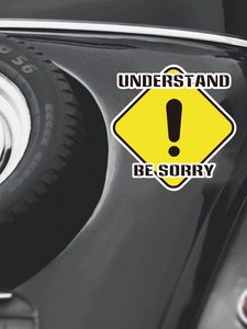 Detail of yellow diamond warning sticker with exclamation mark on black car exterior