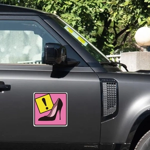 Pink high heel warning sticker with exclamation mark on grey luxury vehicle door