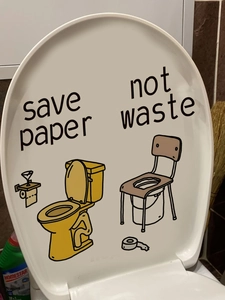 Detail shot of 'Save Paper' toilet lid sticker with yellow toilet bowl illustration