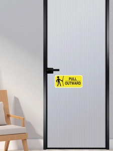 Nahaufnahme eines gelben Pull Outward Türaufklebers mit Symbol auf einer Glastür