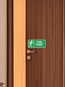 Detail eines grünen PVC-Schiebetürschilds mit PUSH INSIDE Text auf braunem Holz