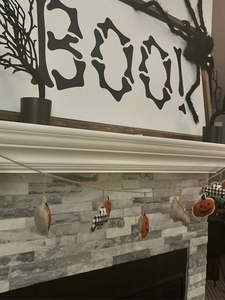 Close-up of Halloween banner with orange pumpkins and buffalo plaid pendants on a mantel