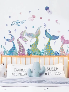 Watercolor mermaid tails and jellyfish wall stickers decorating a cozy bedroom wall