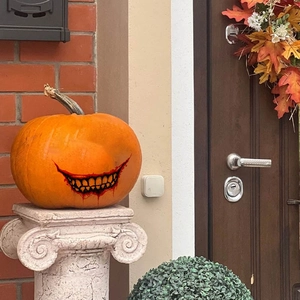 Halloween Kürbis Dekoration mit bösem Lächeln und Blutmuster auf weißem Steinsockel