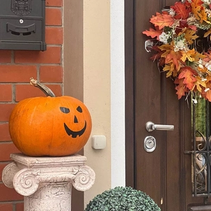 Minimalist white square smart home motion sensor mounted on wall with pumpkin decor