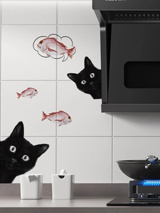 Detail of funny peeping black cat wall decals and red fish stickers on kitchen tiles