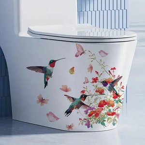 Floral toilet lid sticker with colorful hummingbirds and butterflies on a white ceramic surface