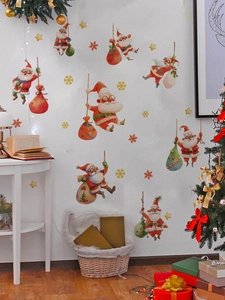 Détail de stickers Père Noël avec sacs de cadeaux rouges et étoiles dorées sur mur blanc