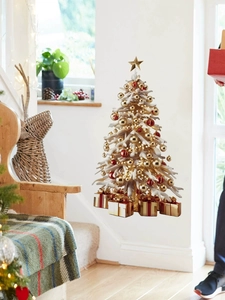 Close-up of small tabletop Christmas tree with gold star topper and red ornaments