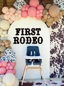 Close-up of baby high chair with dark grey cushion and wooden legs in rodeo party scene