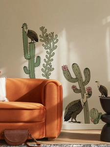 Detailed view of cactus and vulture wall stickers styled above an orange velvet sofa