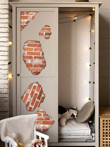 Detailed view of 3D red brick wall decals applied on a light grey wooden wardrobe surface