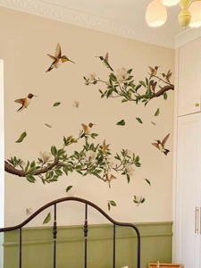 Close-up of hummingbird and white magnolia flower branch wall decals in a bedroom setting