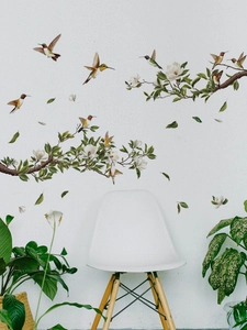 Detail of hummingbird and magnolia tree branch wall decals on a white wall