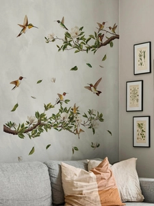 Detail of hummingbird and magnolia wall stickers decorating a cozy living room sofa wall