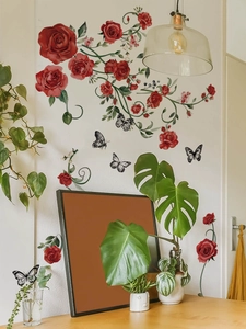 Dettaglio di adesivi murali rose rosse e farfalle su una parete bianca del soggiorno