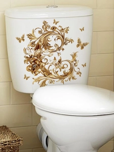 Detail of golden butterfly wall stickers with baroque floral pattern on a toilet tank
