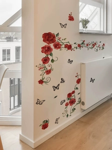 Adesivi murali con rose rosse, rampicanti verdi e farfalle su una parete bianca di casa