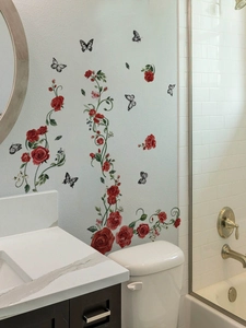 Adesivi murali con rose rosse e farfalle applicati sulle piastrelle bianche del bagno moderno