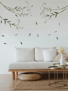 Living room setting showing green vine wall stickers and watercolor leaves on white wall