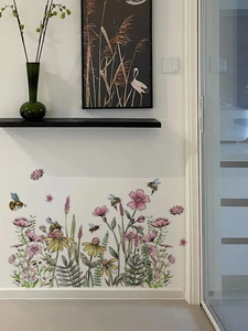 Détail de stickers muraux fleurs sauvages et abeilles sur un mur blanc d'intérieur